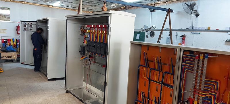 Technicians inspecting and wiring a switchgear panel at Ocean Wind Switchgear workshop in Oman