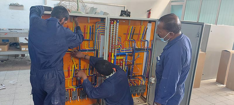 Electrical engineers performing installation and wiring on LV switchgear panels in Oman